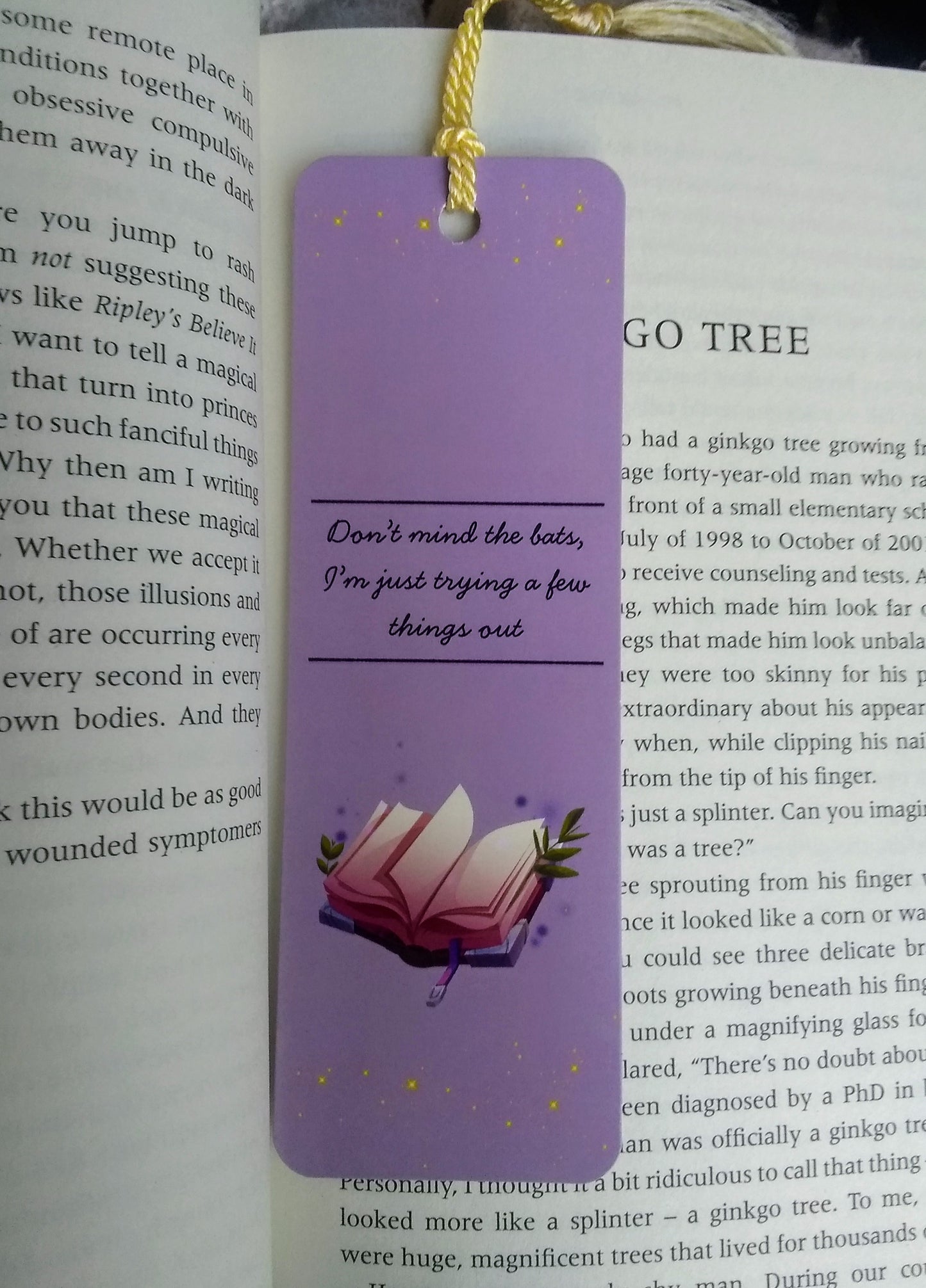 Purple bookmark with the text 'don't mind the bats, I'm just trying a few things out' and a spellbook illustration on an open book