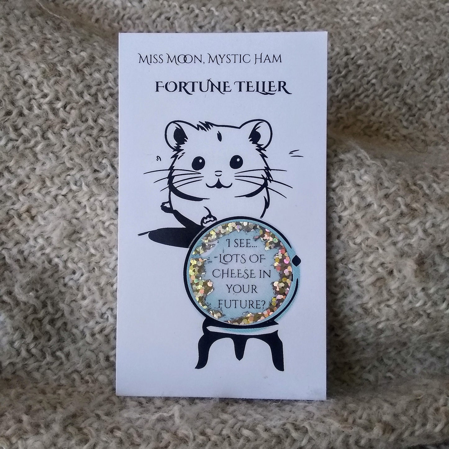Fortune teller card with a hamster and crystal ball on a textured surface