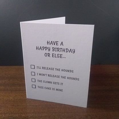 Birthday card with humorous text and checkboxes on a wooden surface with a dark background