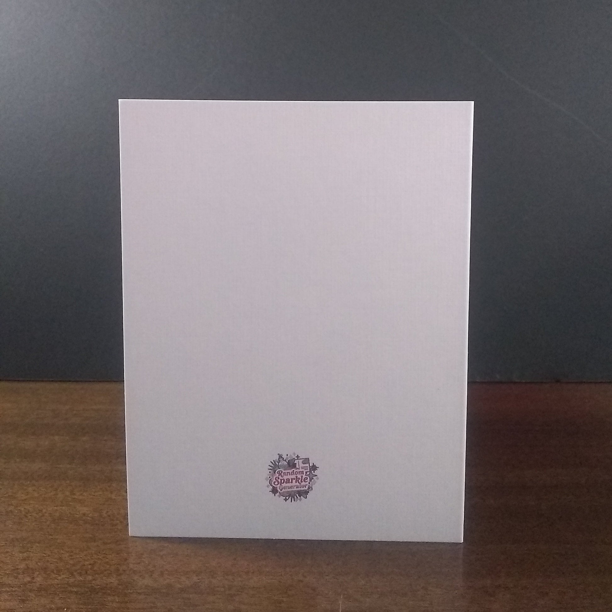 White greeting card with a logo on a wooden surface and dark gray background
