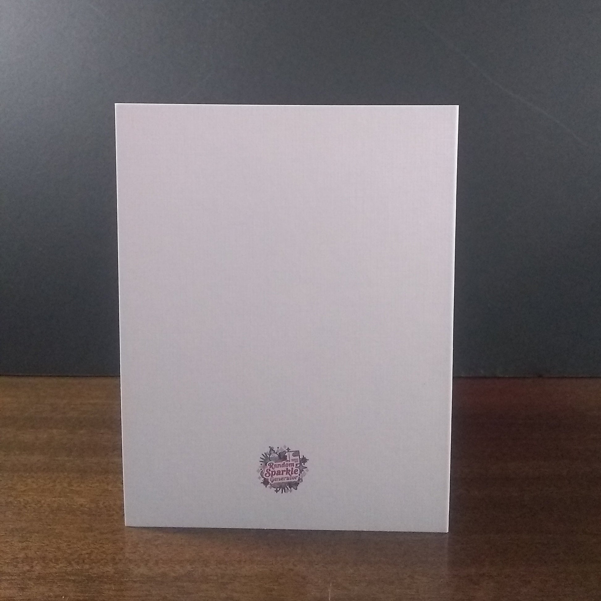 White greeting card with a logo on a wooden surface and dark gray background
