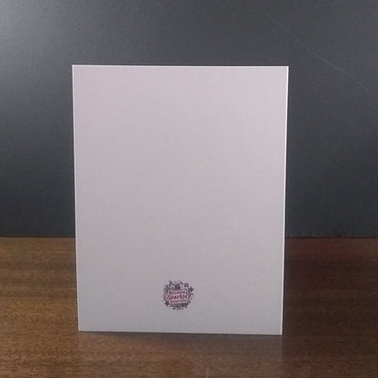 White greeting card with a logo on a wooden surface and dark gray background
