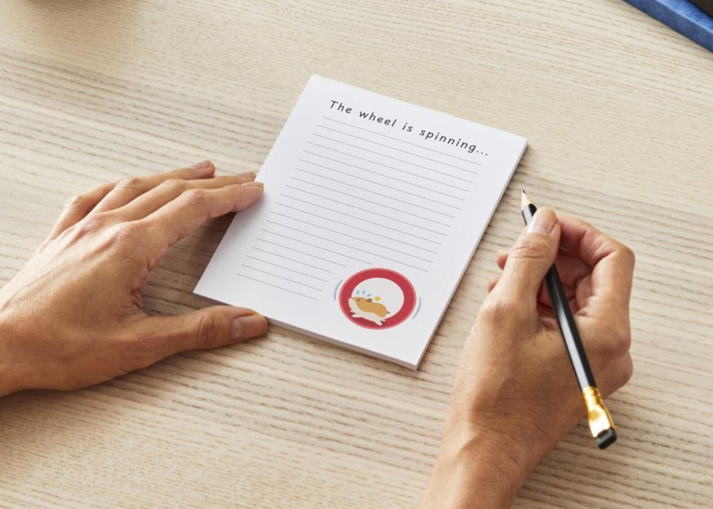 Person holding a pen over a notepad saying 'The wheel is spinning...' at the top and a hamster running on a wheel in the bottom right corner. 