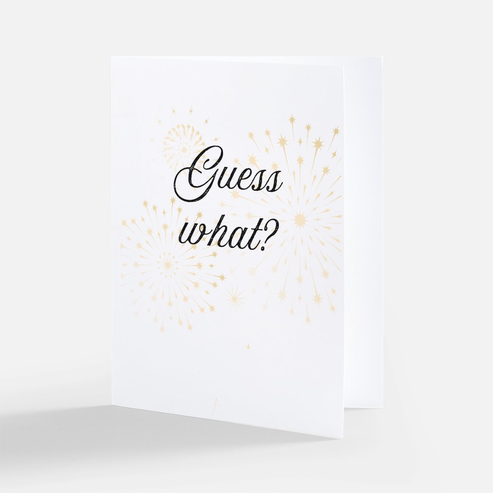 White card with the text 'Guess what?' on the front on a white background