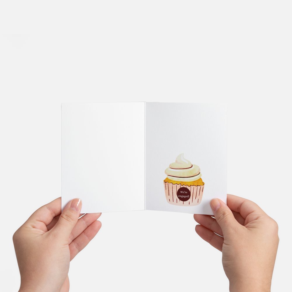 Hands holding a card with a cupcake illustration on a white background